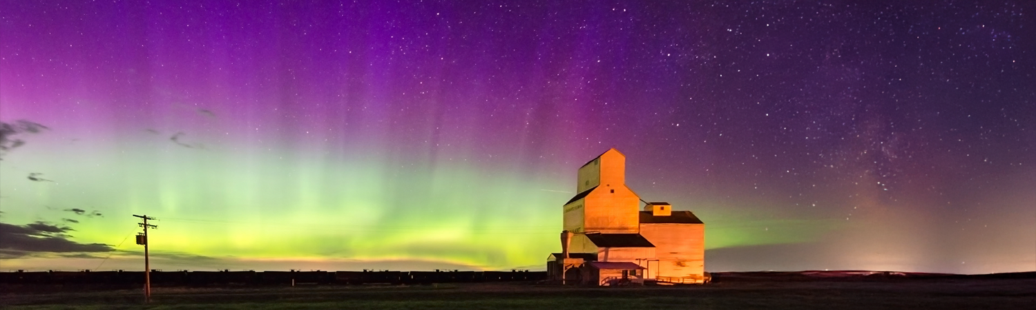 aurora borealis over farm house and field